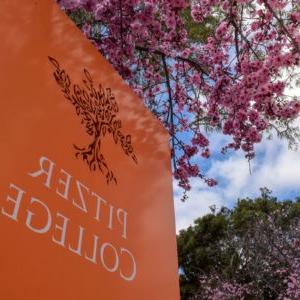 Pitzer College orange sign with pink ornamental plum blossoms